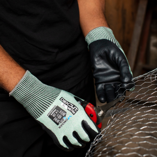 A person wearing gloves holding a pair of scissors, ready to use them for a task or project.